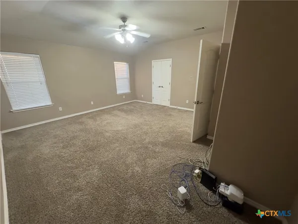 en empty room with windows and ceiling fan