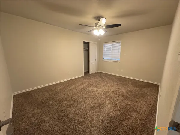 an empty room with a chandelier fan and windows