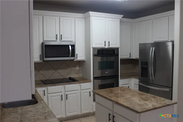 a kitchen with stainless steel appliances granite countertop a refrigerator stove and microwave