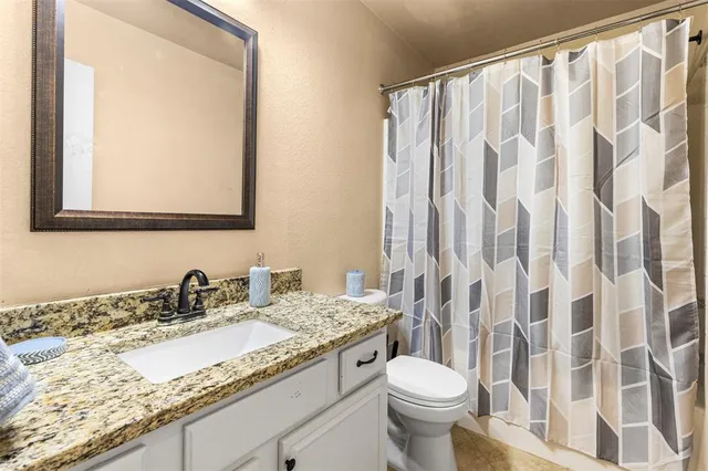 a bathroom with a granite countertop sink a toilet and a mirror