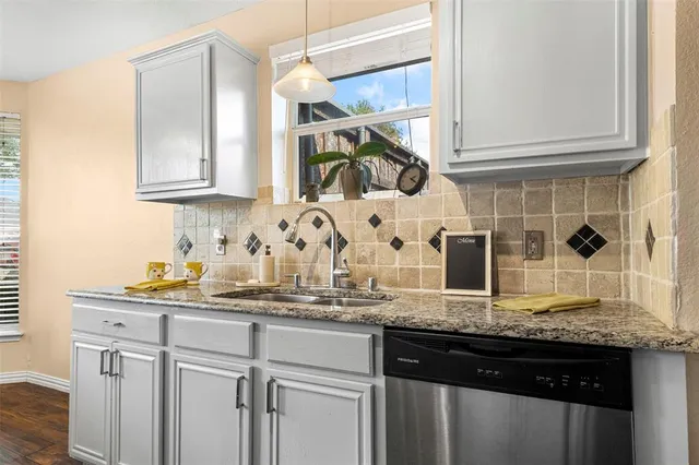 a kitchen with granite countertop a sink a stove and cabinets