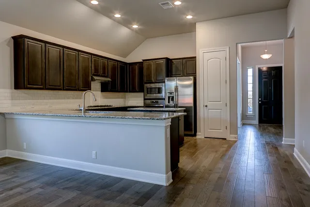a kitchen with stainless steel appliances granite countertop a refrigerator and a stove top oven