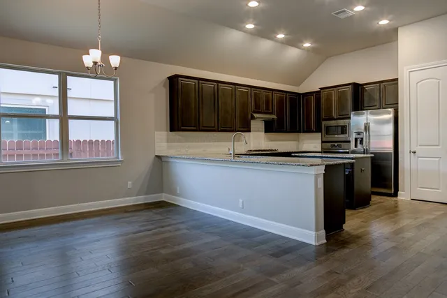 a kitchen with kitchen island a counter top space stainless steel appliances and a window
