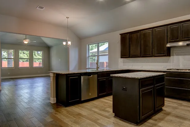 a kitchen with stainless steel appliances granite countertop a stove a sink and a microwave