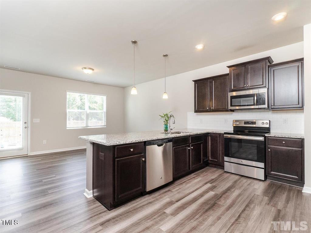 8862 Common Townes Drive Raleigh, NC 27616 - Photo 2 of 13 a large kitchen with stainless steel appliances granite countertop a stove a sink dishwasher and a microwave oven with wooden floor