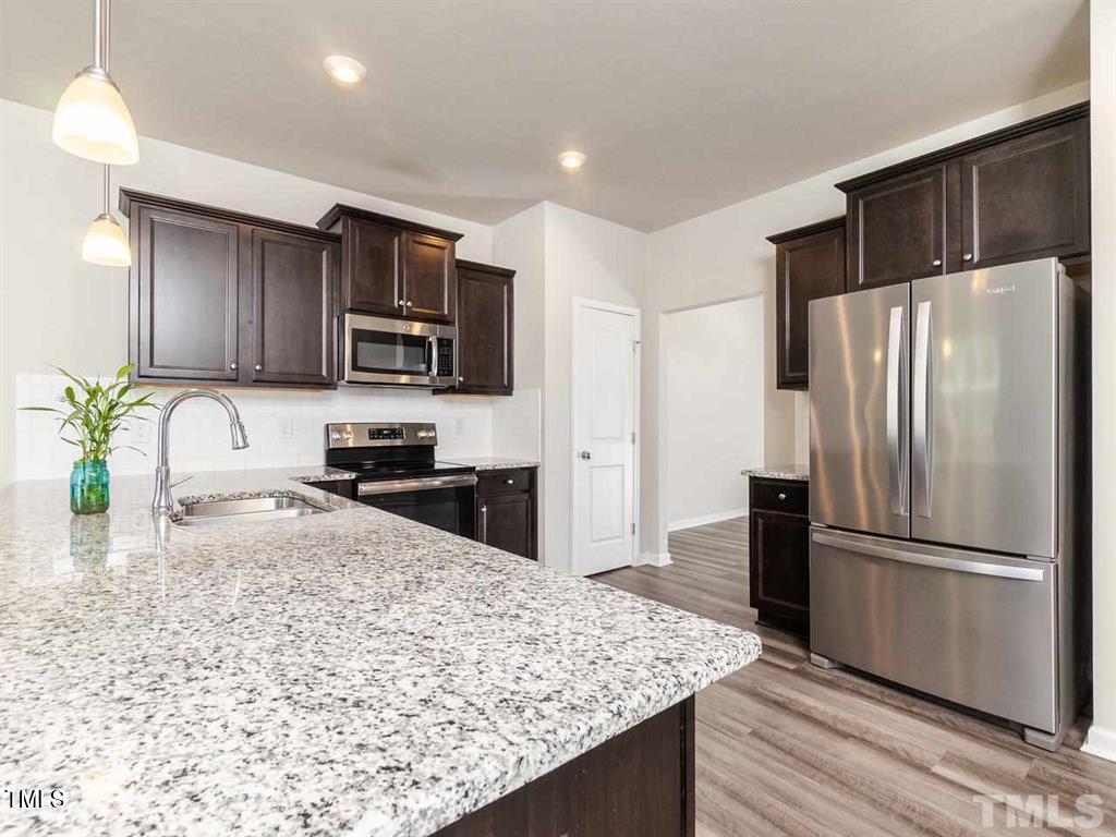8862 Common Townes Drive Raleigh, NC 27616 - Photo 3 of 13 a kitchen with granite countertop a refrigerator and a sink