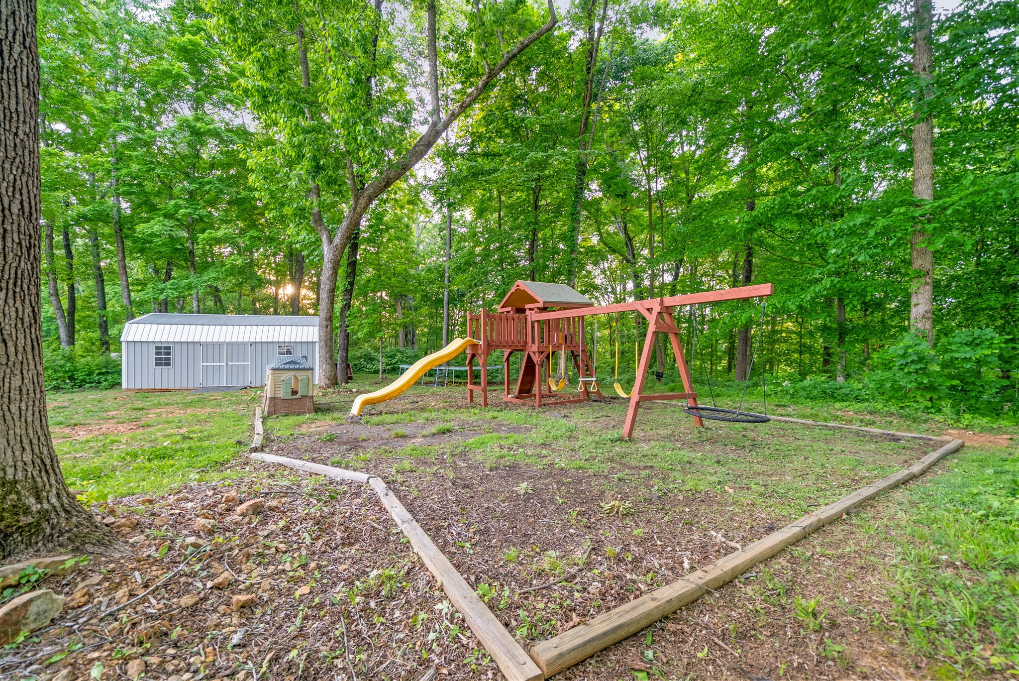 2685 Mockingbird Hill Road Palmyra, TN 37142 - Photo 46 of 47 a view of a backyard with a slide trees and wooden fence