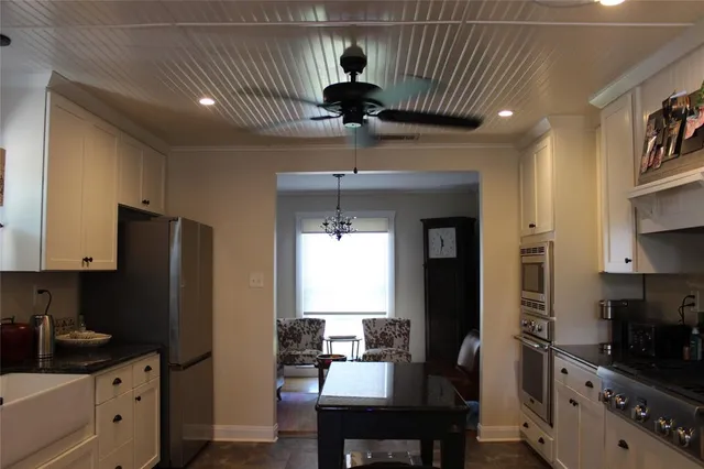 a kitchen with stainless steel appliances a dining table chairs refrigerator and sink