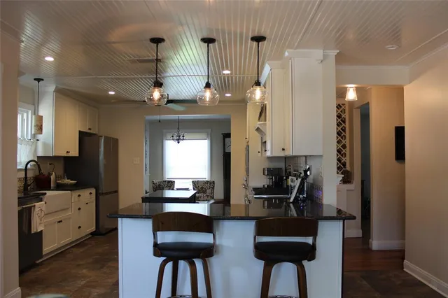 a kitchen with stainless steel appliances kitchen island granite countertop a refrigerator and a stove top oven