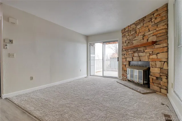 a view of an empty room with a fireplace and a window