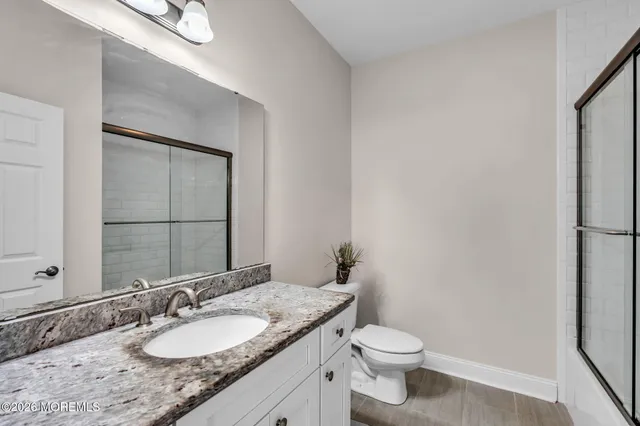 a bathroom with a granite countertop sink toilet and mirror