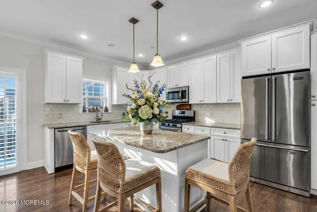 a kitchen with kitchen island granite countertop a refrigerator a stove a center island a dining table and chairs