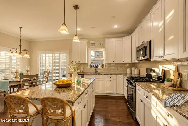 a kitchen with stainless steel appliances granite countertop a sink a stove and a wooden floors
