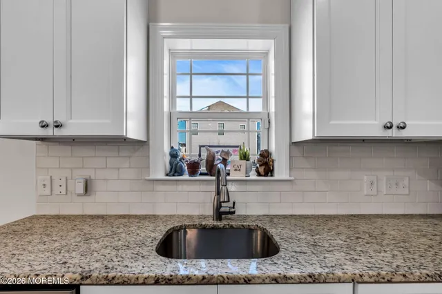 a kitchen with granite countertop a sink and white cabinets