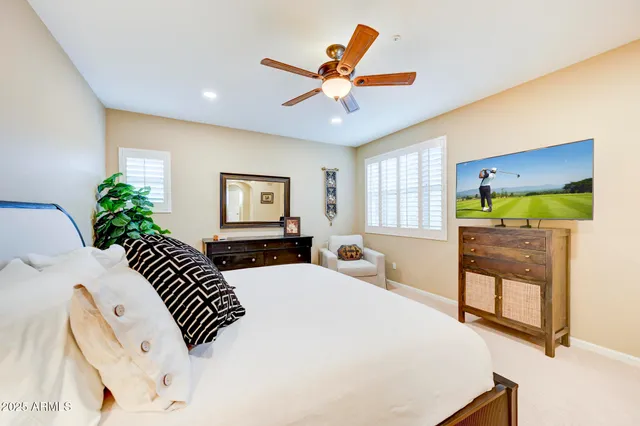 a bedroom with a bed a couch and a flat tv screen on the dresser