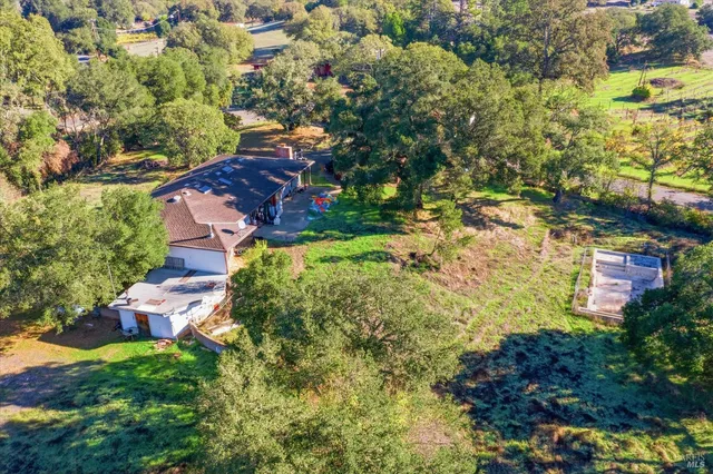 an aerial view of residential house with outdoor space and trees all around