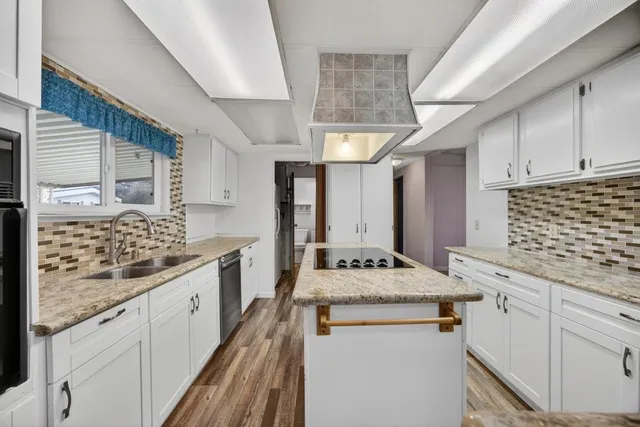 a kitchen with granite countertop a sink stove and cabinets