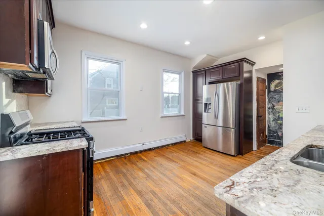 a kitchen with stainless steel appliances granite countertop a refrigerator a stove and a wooden floors