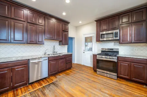a kitchen with stainless steel appliances granite countertop wooden cabinets a stove top oven a sink and dishwasher
