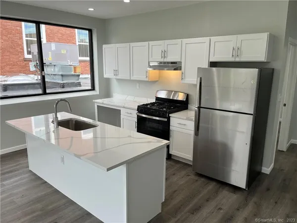 a kitchen with stainless steel appliances a refrigerator a sink a stove a microwave a counter space and a window