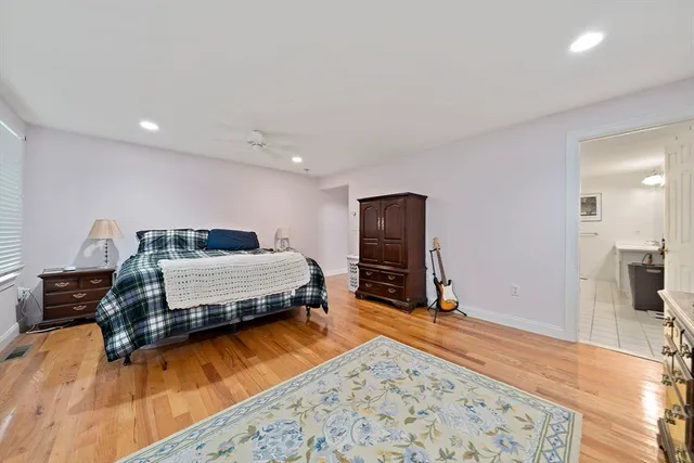a bedroom with a bed and a dresser with wooden floor