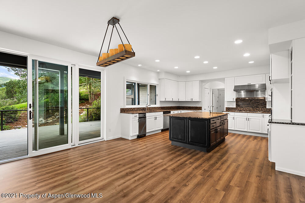 400 Medicine Bow Road Aspen, CO 81611 - Photo 10 of 58 a kitchen with stainless steel appliances kitchen island granite countertop a stove a refrigerator a sink and a oven with wooden floor