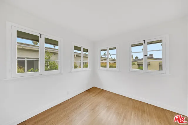 a view of empty room with wooden floor and windows