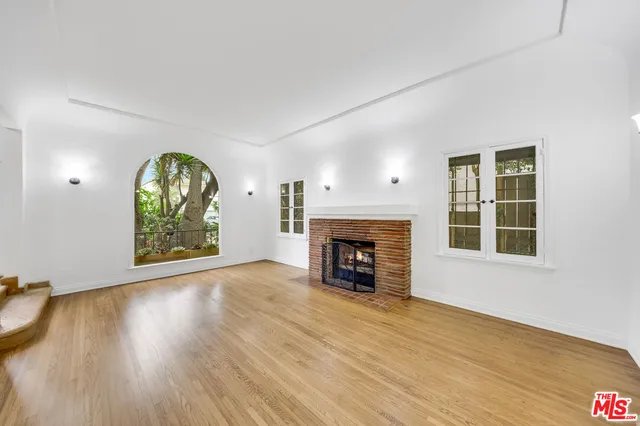 an empty room with windows fireplace and wooden floor