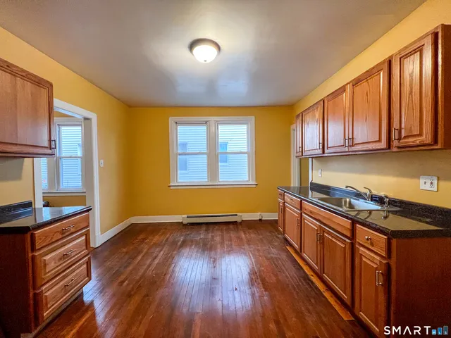 a kitchen that has a sink wooden floor stainless steel appliances and cabinets