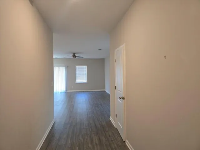 a view of a hallway with wooden floor and a window