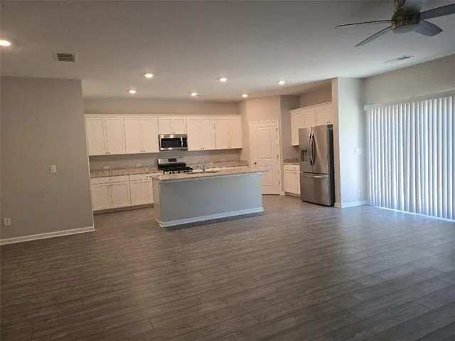 a kitchen with stainless steel appliances granite countertop a refrigerator and a stove top oven