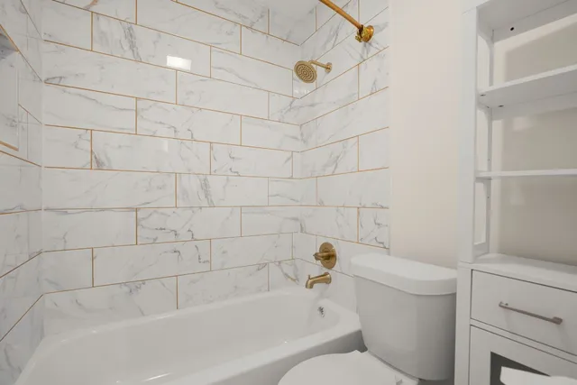 a bathroom with a granite countertop sink a toilet and shower