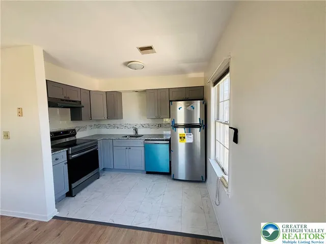 a kitchen with stainless steel appliances granite countertop a sink a stove cabinets and wooden floor