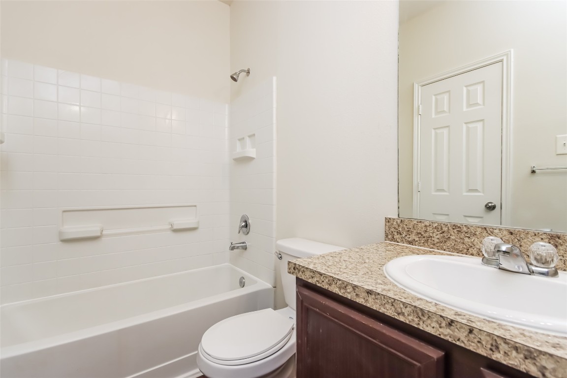12414 Roy Mix Bohn Lane Houston, TX 77044 - Photo 10 of 13 a bathroom with a granite countertop sink a toilet and bathtub