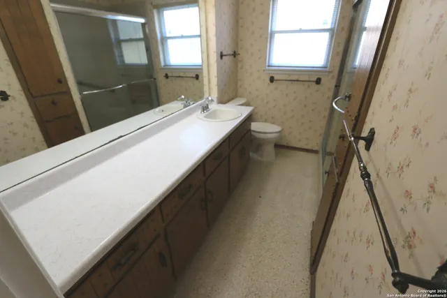 an empty room with a chandelier fan and windows