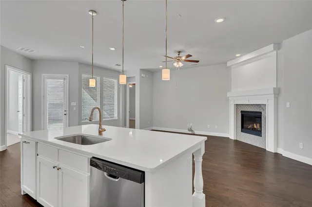 a kitchen with a sink chandelier and living room view