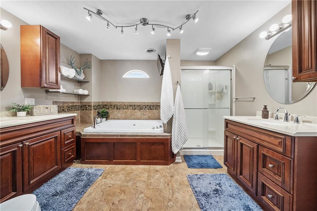 3032 Investors Road Washington, PA 15301 - Photo 25 of 50 Owner’s suite positioned in its own private section of the home, offering a spacious bedroom, walk-in closet with custom organization, and a spa-style bathroom with soaking tub, dual vanities, stand-up shower, and stackable washer and dryer.