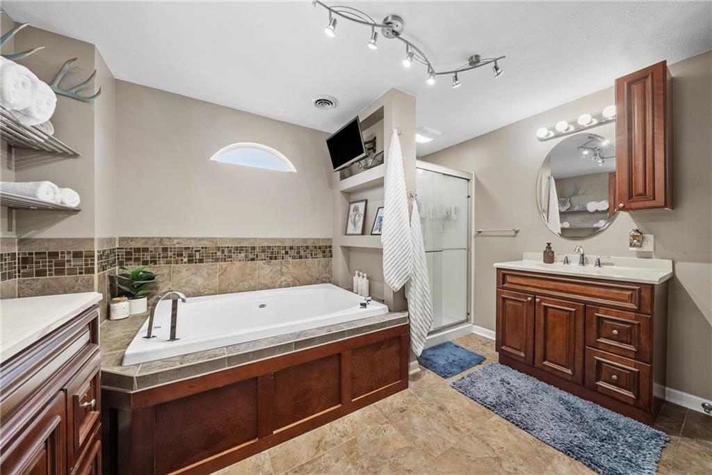 3032 Investors Road Washington, PA 15301 - Photo 26 of 50 Owner’s suite positioned in its own private section of the home, offering a spacious bedroom, walk-in closet with custom organization, and a spa-style bathroom with soaking tub, dual vanities, stand-up shower, and stackable washer and dryer.