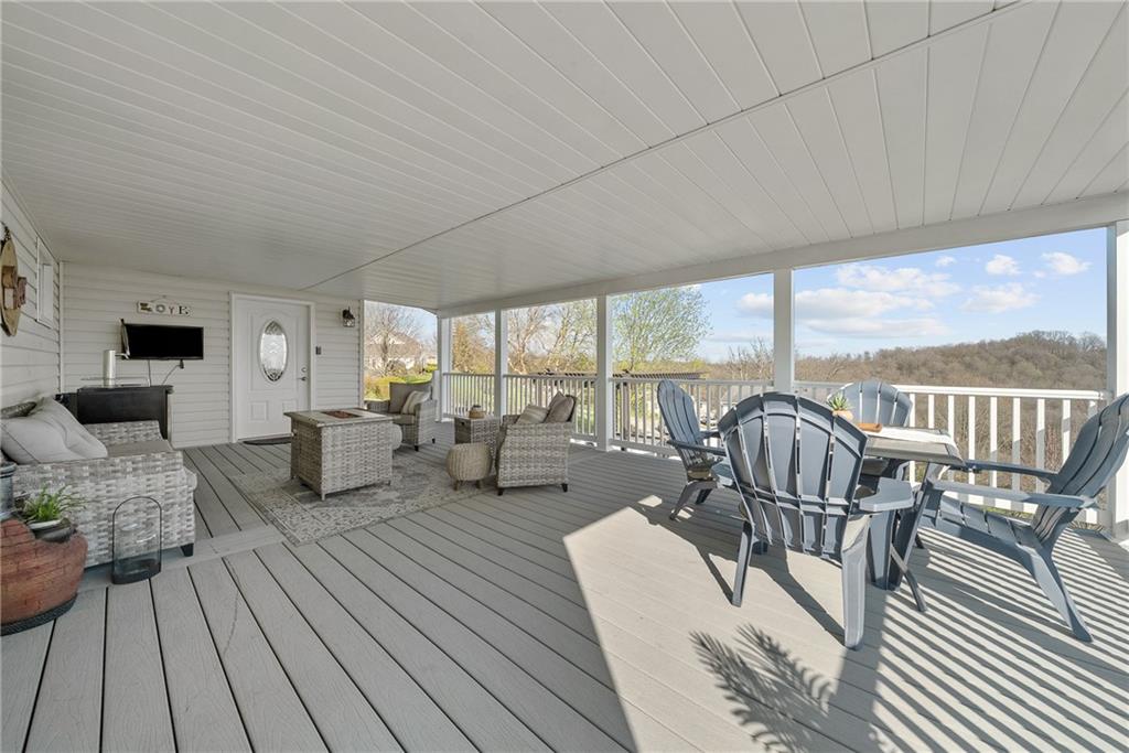 3032 Investors Road Washington, PA 15301 - Photo 39 of 50 Expansive 27x15 covered composite deck, flows directly from the kitchen and dining area with steps to the lower yard, creating an ideal setting for entertaining, outdoor dining, firepit evenings, and sunset views.