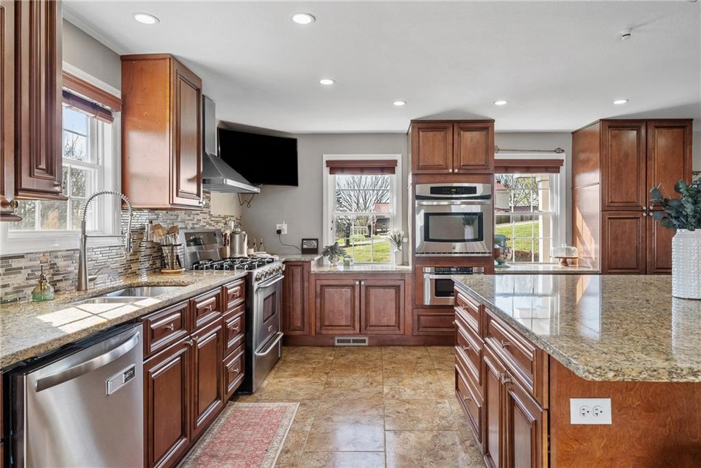 3032 Investors Road Washington, PA 15301 - Photo 5 of 50 A true centerpiece of the home, this 26x22 open kitchen and dining area is built for gathering. A 6.5x6.5 island anchors the space with seating for six or more, surrounded by custom cabinetry, granite countertops, a built-in wall oven and microwave, professional-grade refrigerator, and a Kenmore Elite 5-burner gas stove with vent hood.