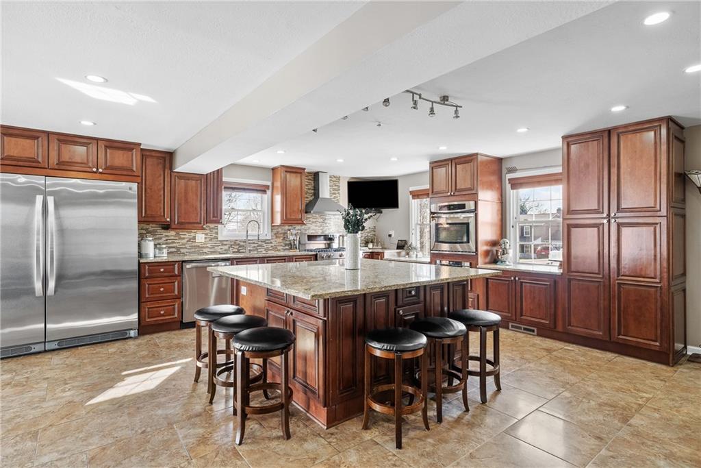 3032 Investors Road Washington, PA 15301 - Photo 6 of 50 A true centerpiece of the home, this 26x22 open kitchen and dining area is built for gathering. A 6.5x6.5 island anchors the space with seating for six or more, surrounded by custom cabinetry, granite countertops, a built-in wall oven and microwave, professional-grade refrigerator, and a Kenmore Elite 5-burner gas stove with vent hood.