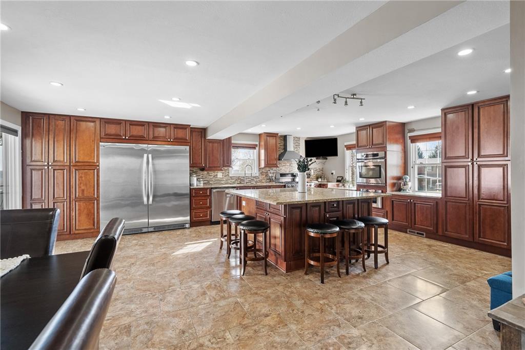 3032 Investors Road Washington, PA 15301 - Photo 9 of 50 A true centerpiece of the home, this 26x22 open kitchen and dining area is built for gathering. A 6.5x6.5 island anchors the space with seating for six or more, surrounded by custom cabinetry, granite countertops, a built-in wall oven and microwave, professional-grade refrigerator, and a Kenmore Elite 5-burner gas stove with vent hood.