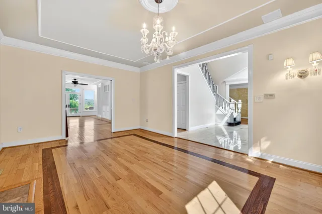 a view of an empty room with wooden floor and a ceiling fan