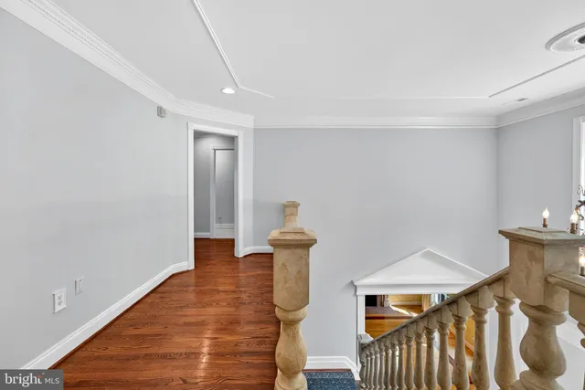 a view of a hallway with wooden floor and a bathroom