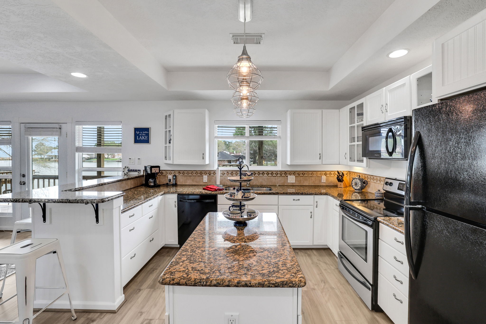331 Holiday Lane Coldspring, TX 77331 - Photo 17 of 36 This bright kitchen features white cabinetry, granite countertops, and stainless steel appliances. There's a central island, ample natural light from large windows, and a partial view of the outdoors, creating an inviting and functional space.