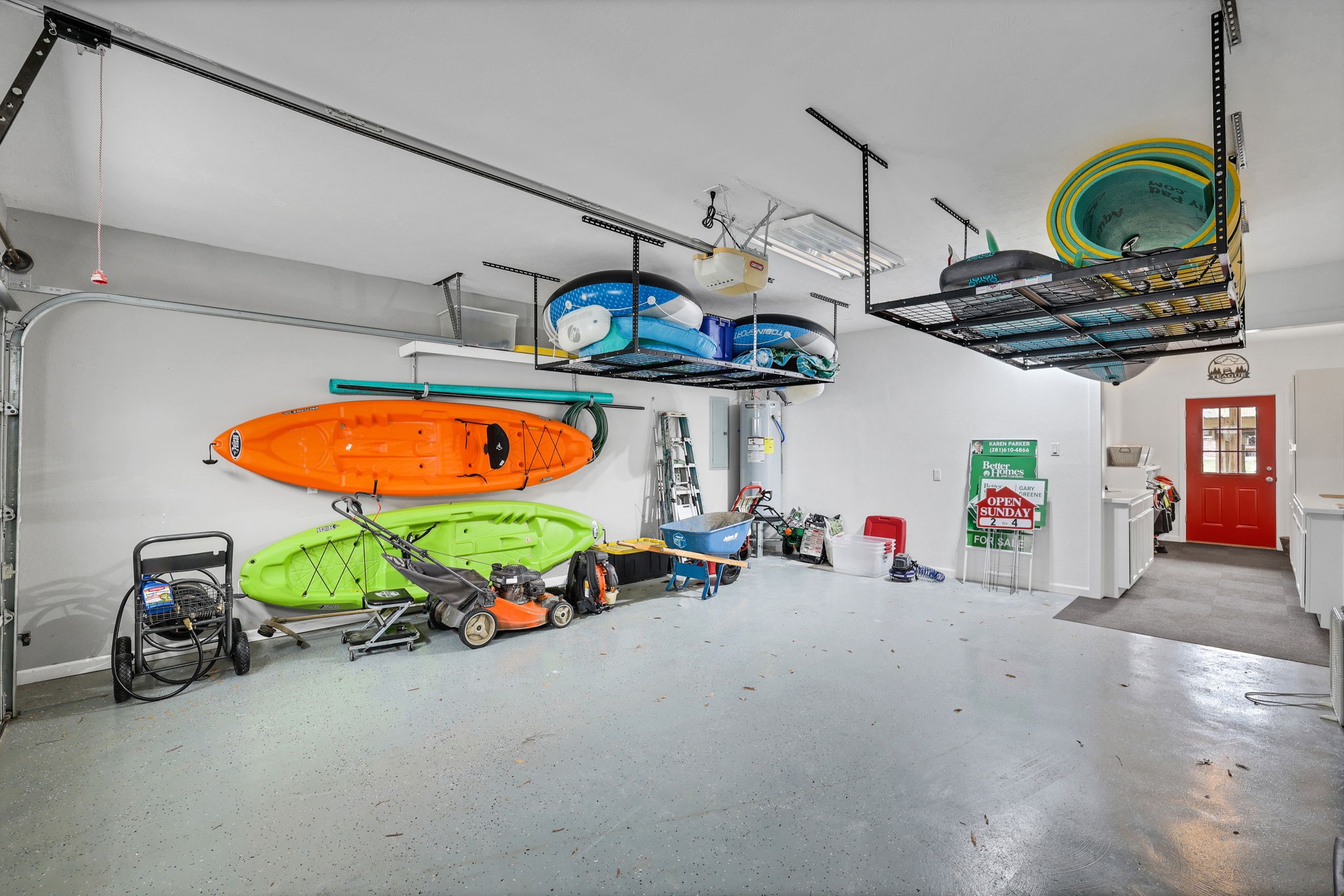 331 Holiday Lane Coldspring, TX 77331 - Photo 24 of 36 Spacious garage with ample storage, featuring wall-mounted kayak racks, overhead shelving, and a workbench area. Ideal for outdoor enthusiasts and organized living.