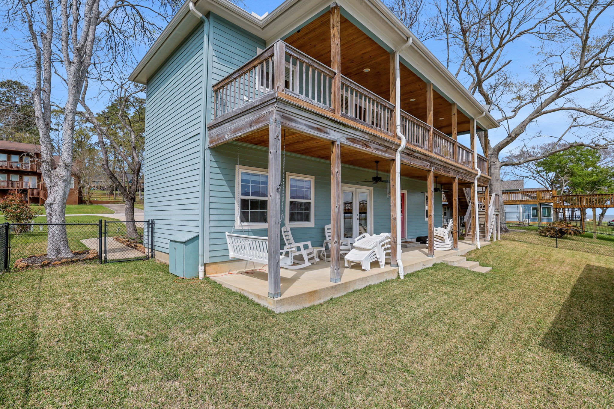 331 Holiday Lane Coldspring, TX 77331 - Photo 27 of 36 Charming two-story home with a spacious, covered balcony and patio, perfect for relaxation. The exterior features rustic wood accents and a well-maintained lawn, offering a serene outdoor space.