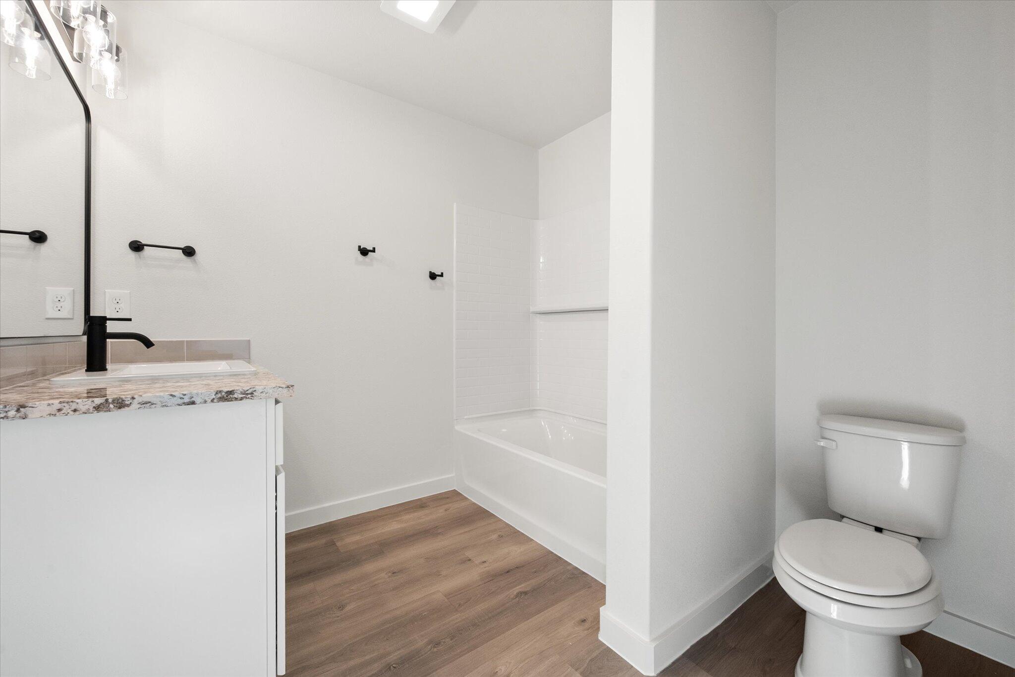 7203 7th Street Lubbock, TX 79416 - Photo 14 of 20 a bathroom with a granite countertop toilet a sink and a mirror