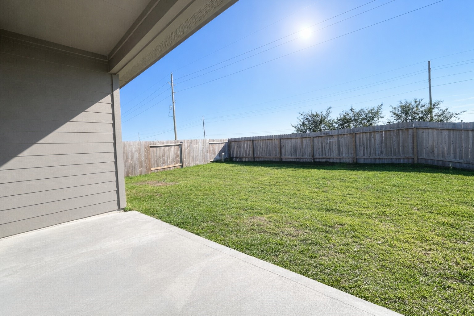 1739 Royal Rim Drive Houston, TX 77014 - Photo 20 of 20 A spacious backyard with a neatly maintained lawn, enclosed by a wooden fence. A covered patio area provides a shaded space perfect for outdoor relaxation or entertaining. The clear blue sky adds to the bright and inviting atmosphere.