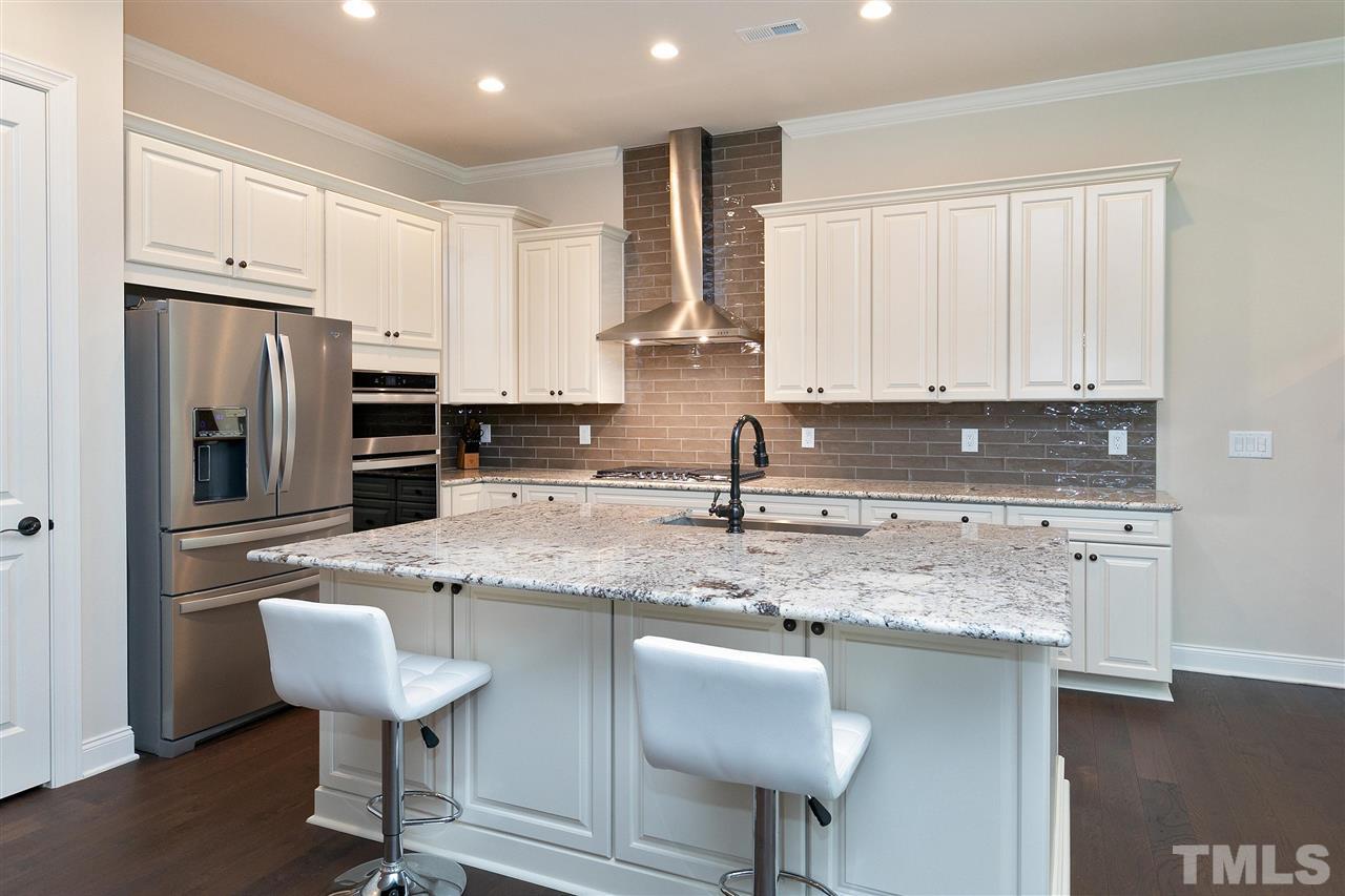 2519 Range Overlook Crossing Apex, NC 27523 - Photo 7 of 26 a kitchen with stainless steel appliances granite countertop a sink a stove a refrigerator island and chairs